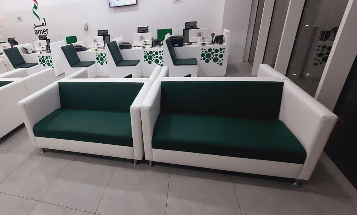 Amer Center waiting area with white and deep-green sofas beside service counters